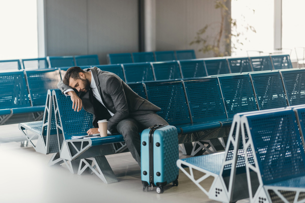 soñoliento joven hombre de negocios esperando el vuelo en el vestíbulo del aeropuerto
 - Foto, Imagen