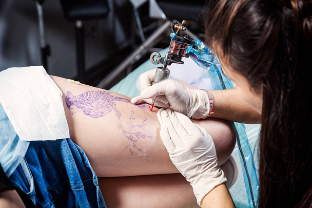 Tattooer nő mutatja a folyamat, hogy a tetoválás madár, a nő. Tetoválás tervezési minta - Fotó, kép