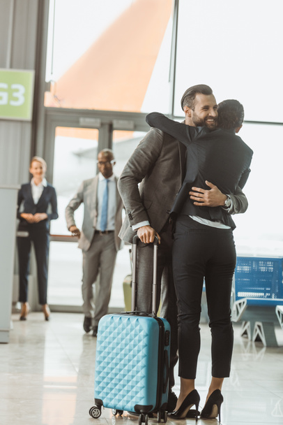 happy young businessman embracing with woman at airport - Φωτογραφία, εικόνα
