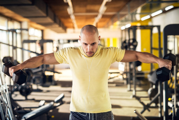 fuerte musculoso hombre ejercitando con mancuernas en gimnasio
  - Foto, Imagen