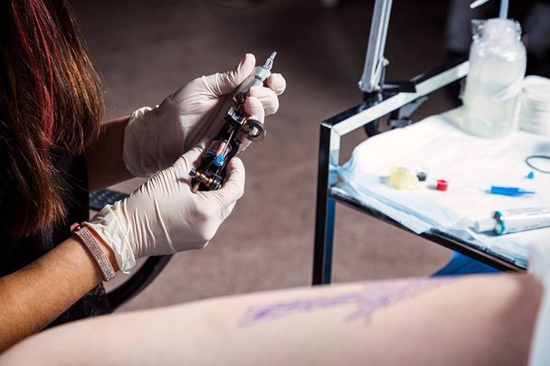 Close-up tatoeëerder op het werk. voorbereiding van de naald en de tattoo machine. - Foto, afbeelding