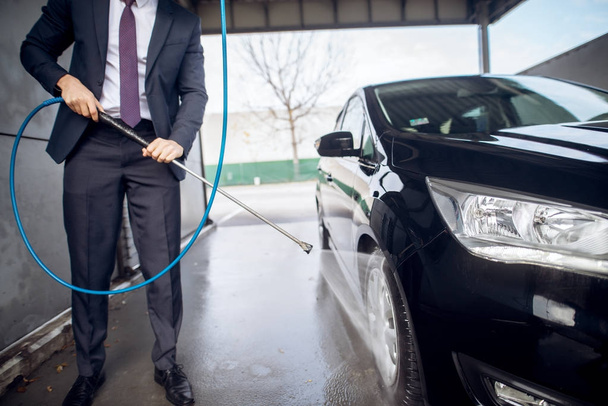 cropped portrait of handsome stylish young man in suit washing car at the manual car washing self-service station - Foto, Imagem