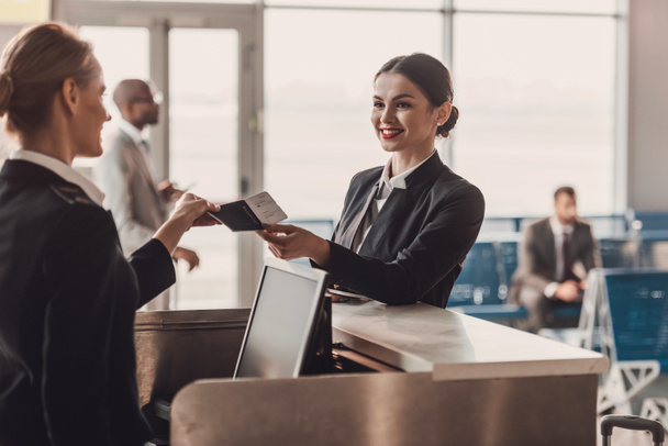 glückliche Geschäftsfrau gibt Pass und Ticket an Mitarbeiter am Flughafen-Check-in-Schalter - Foto, Bild