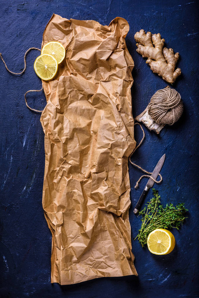 top view of crumpled baking paper with lemon, ginger, rope and knife on blue surface - Photo, image
