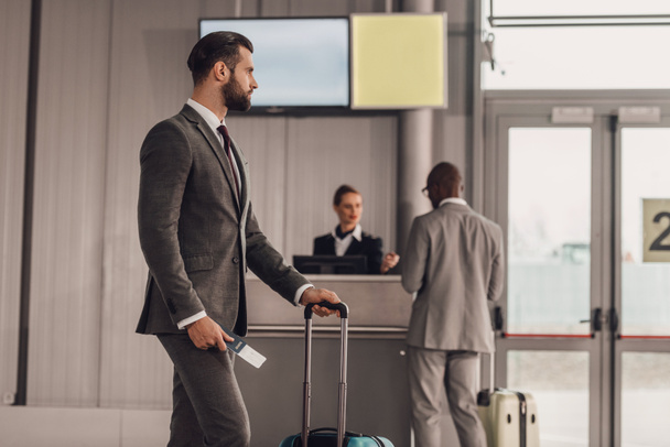 liikemies matkatavaroiden ja lentolippujen kanssa lentokentällä
 - Valokuva, kuva
