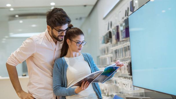 happy young love couple choosing new tv in tech store - 写真・画像