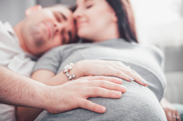 Cheerful pregnant couple relaxing at home and enjoying pregnancy time - 写真・画像