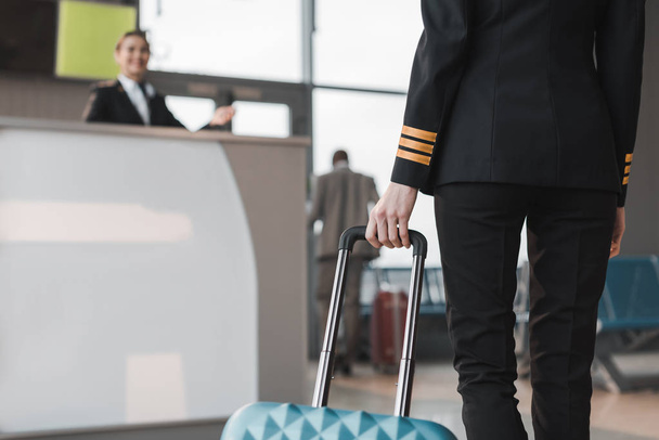 tiro recortado de piloto femenino con maleta en el vestíbulo del aeropuerto
 - Foto, Imagen