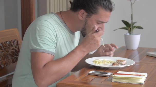 A young man eats a tuna steak with spaghetti. - Video