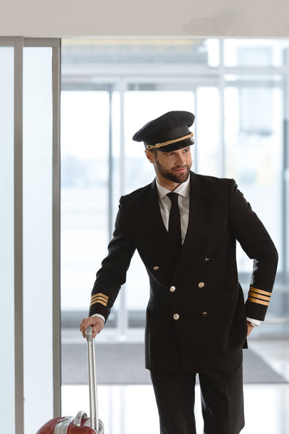 handsome young pilot with suitcase at departure area - Photo, Image