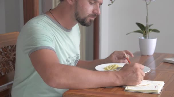 A young man eats a tuna steak with spaghetti. - Filmati, video