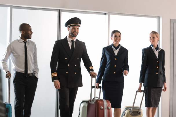 felice squadra di personale dell'aviazione a piedi da loggia aeroporto con valigie
 - Foto, immagini