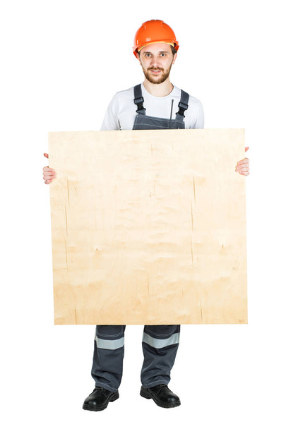 A builder or a worker in a protective helmet with a sheet of ply - Photo, Image