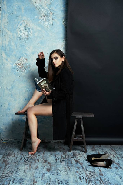 Gorgeouns young fashion model in lingerie and black coat holding book - Foto, afbeelding