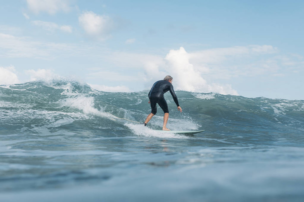 Sportler reitet Welle auf Surfbrett im Ozean  - Foto, Bild