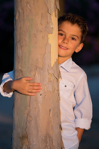 Adorable elegante niño abrazando el árbol
 - Foto, Imagen