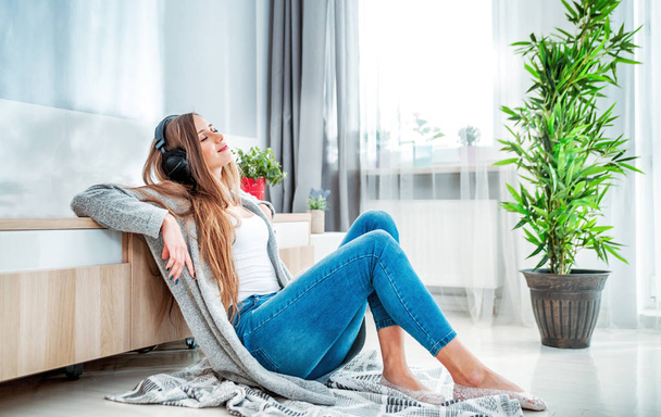 Woman with headphones listening to music at home in living room - Foto, imagen