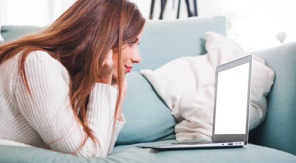 Confident woman at home lying on sofa and working with laptop - Foto, immagini