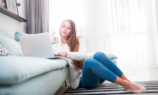 Woman at home using laptop computer on sofa and resting - Photo, Image