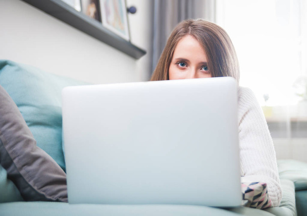 Young woman at home using laptop computer on sofa and resting - Foto, afbeelding