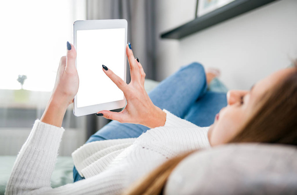 Woman on sofa at home using tablet computer and relaxing - Photo, Image