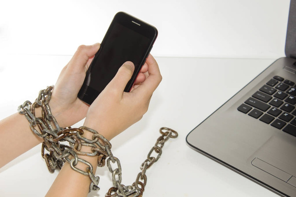 Iron chain ties together hands and smartphone - mobile phone addiction concept. - Photo, Image