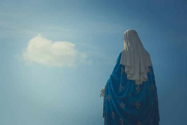 Estatua de la Santísima Virgen María de pie frente a la Catedral de la Inmaculada Concepción en la Diócesis Católica Romana con crucifijo y fondo azul en la provincia de Chanthaburi, Tailandia
. - Foto, Imagen