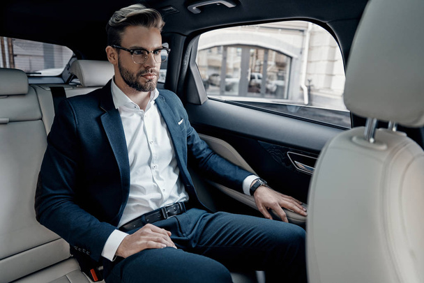Handsome young businessman sitting in back seat of car - Fotó, kép