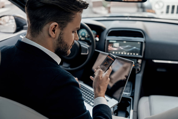 man in formal wear using his smart phone while sitting in the car - Фото, зображення