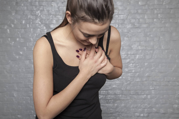 Μια νεαρή γυναίκα κρατά το στήθος, πιθανή καρδιακή προσβολή ή άλ - Φωτογραφία, εικόνα