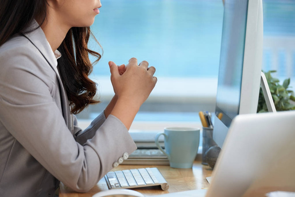 Обрізане зображення молодої бізнес-леді, що читає інформацію на екрані комп'ютера
 - Фото, зображення