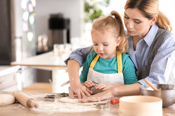 Mother and daughter with dough at table indoors - Фото, зображення