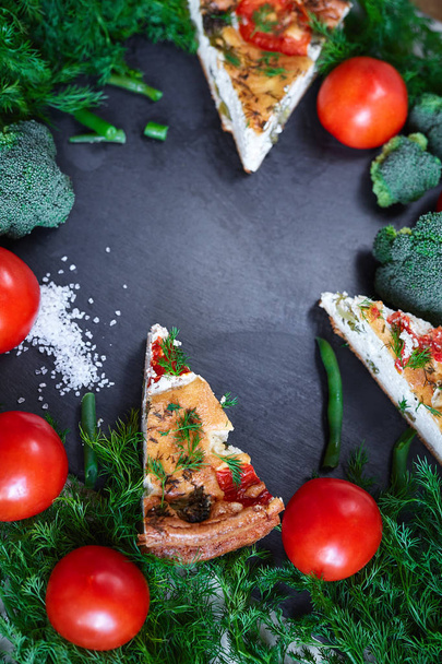 pieces of vegetable pie with cottage cheese, tomatoes, dill and asparagus beans on a dark ceramic background. - Photo, image