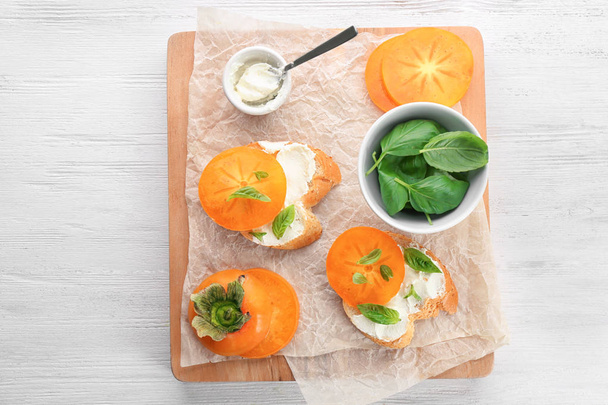 Tasty bruschettas with persimmon on wooden board - Foto, imagen