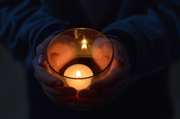 manos alrededor de una vela encendida como reloj de noche
 - Foto, Imagen