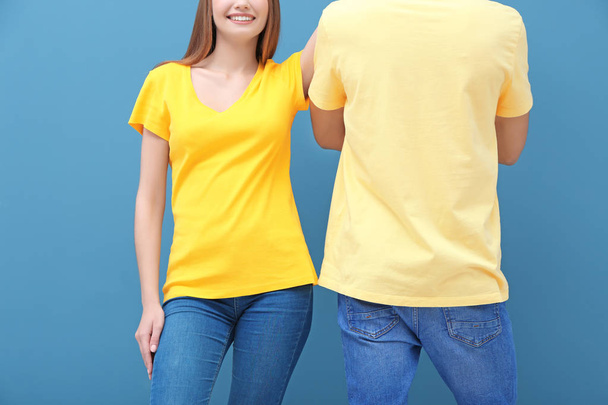 Young woman and man in yellow t-shirts on color background. Mockup for design - Zdjęcie, obraz