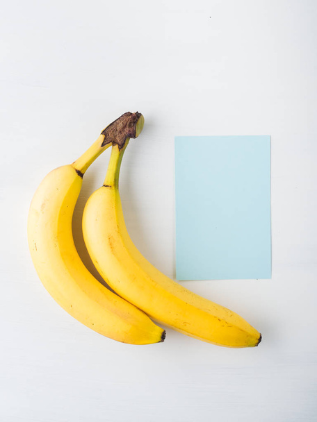 Due banane su bianco con cartellino blu
 - Foto, immagini
