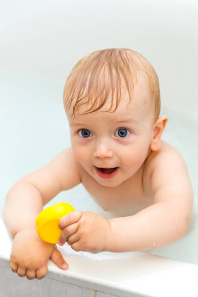 Adorable niño sentado en el baño y jugando con el pato de goma
 - Foto, Imagen