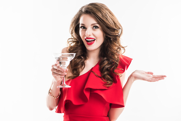 surprised fashionable girl in red dress holding glass of cocktail isolated on white - Фото, зображення
