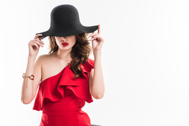 attraente ragazza alla moda nascondendo gli occhi sotto il cappello nero isolato su bianco
 - Foto, immagini