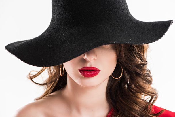 mujer atractiva ocultando los ojos bajo sombrero negro aislado en blanco
 - Foto, Imagen