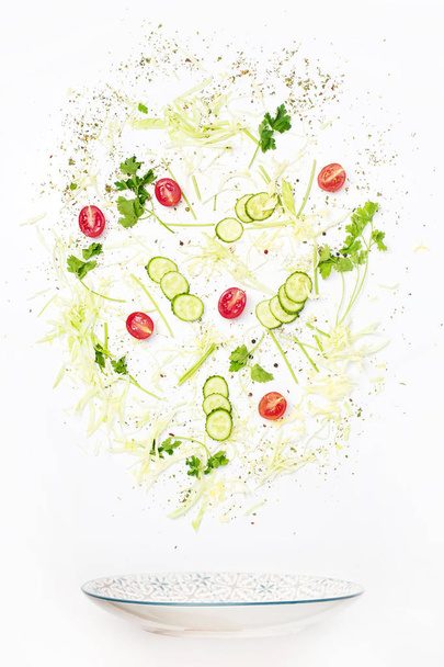The salad bowl in flight with vegetables: tomato, cucumber, cabbage on white background - Photo, Image