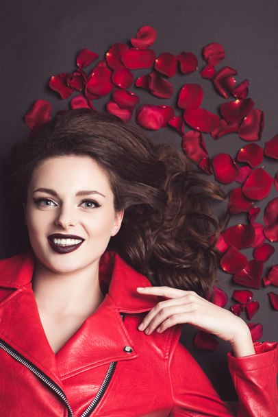 top view of smiling girl lying with roses petals, valentines day concept  - 写真・画像