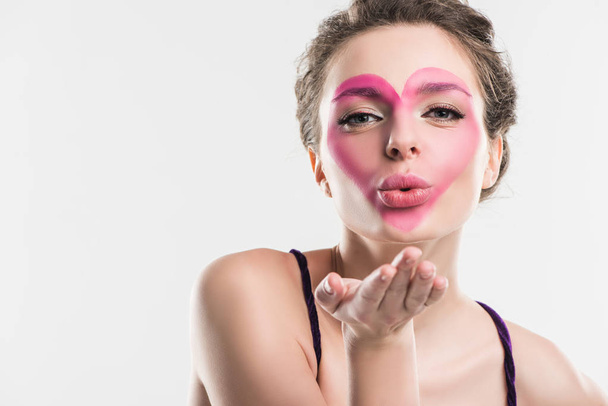 girl with painted pink heart on face sending air kiss isolated on white, valentines day concept - Photo, Image
