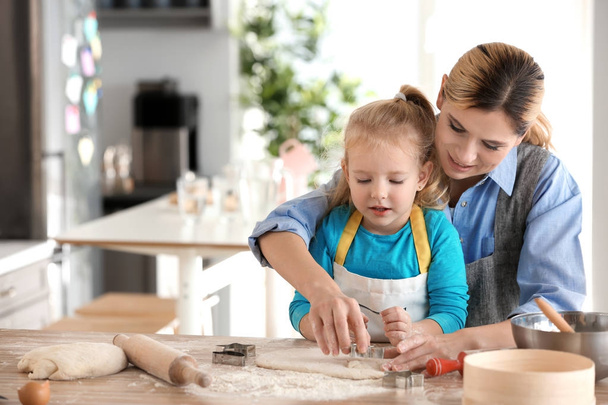Mother and daughter with dough at table indoors - Photo, Image