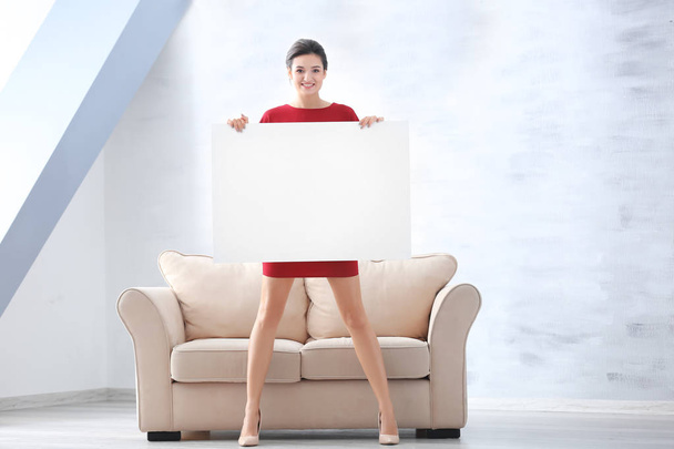 Young woman with blank advertising board indoors - Photo, Image