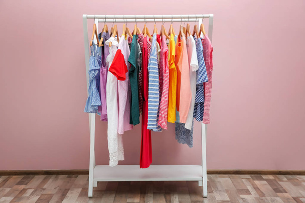 Rack with different clothes near color wall - Photo, Image