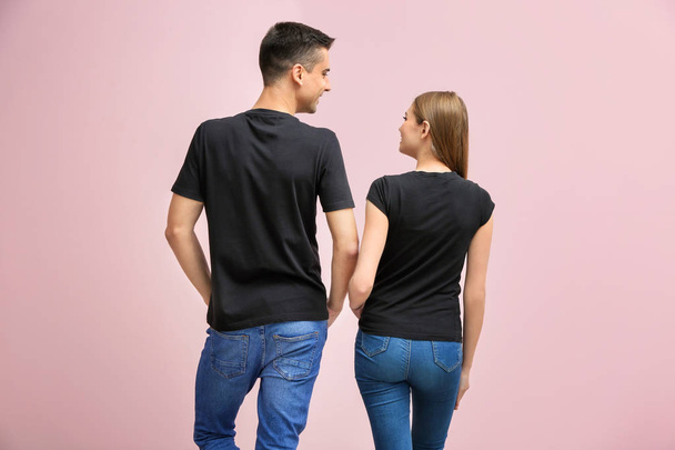 Young woman and man in black t-shirts on color background. Mockup for design - Foto, immagini