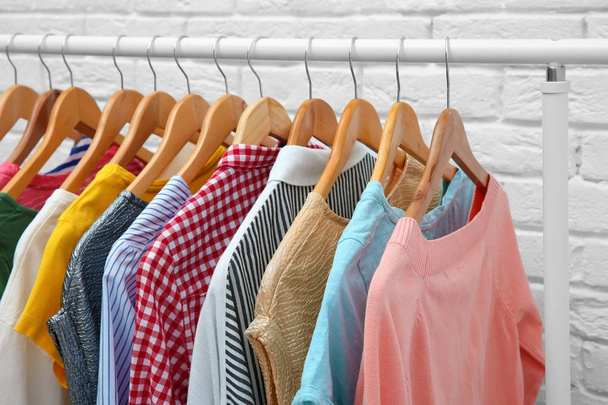 Rack with different clothes near brick wall - Φωτογραφία, εικόνα