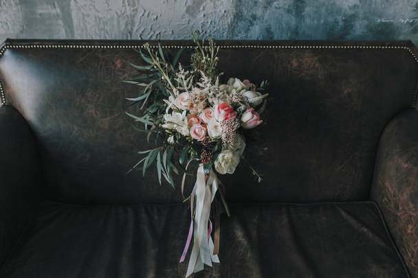 Rustic wedding bouquet with light roses and other flowers on a luxury brown sofa. Close-up. - Foto, Imagem